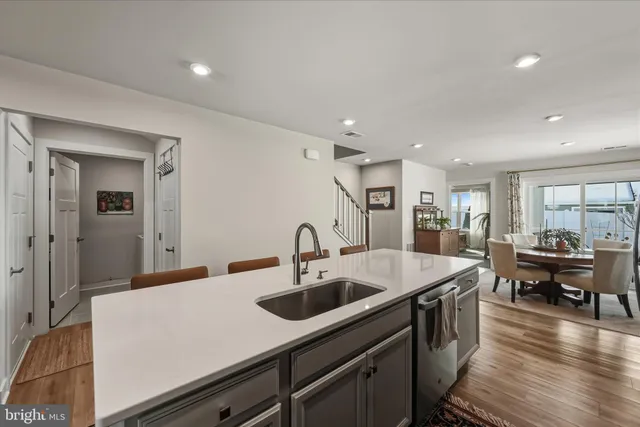 a kitchen with sink refrigerator and couches with wooden floor