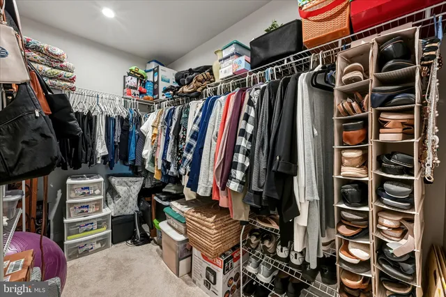a view of walk in closet with clothes and shoes