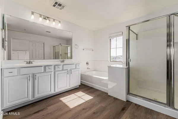 a spacious bathroom with a double vanity sink a mirror and a bathtub