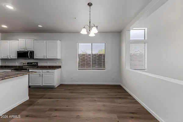 a kitchen with stainless steel appliances granite countertop a stove a sink and white cabinets with wooden floor