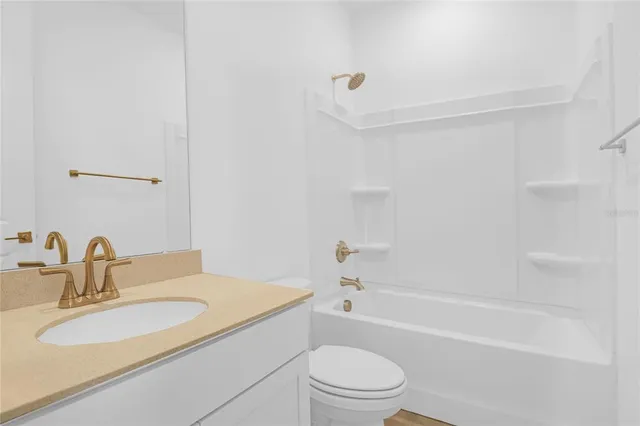 a bathroom with a bathtub shower sink vanity mirror and toilet