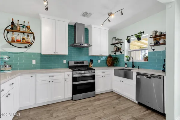 a kitchen with cabinets stainless steel appliances and wooden floor