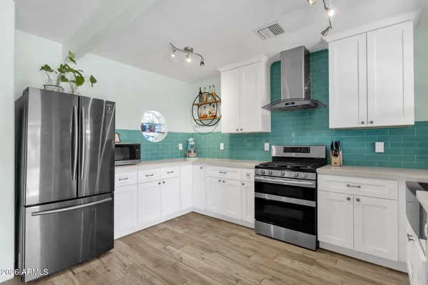 a kitchen with stainless steel appliances granite countertop a kitchen island hardwood floor and a sink
