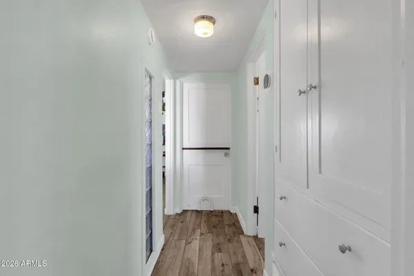 a view of a hallway with wooden floor and a bathroom