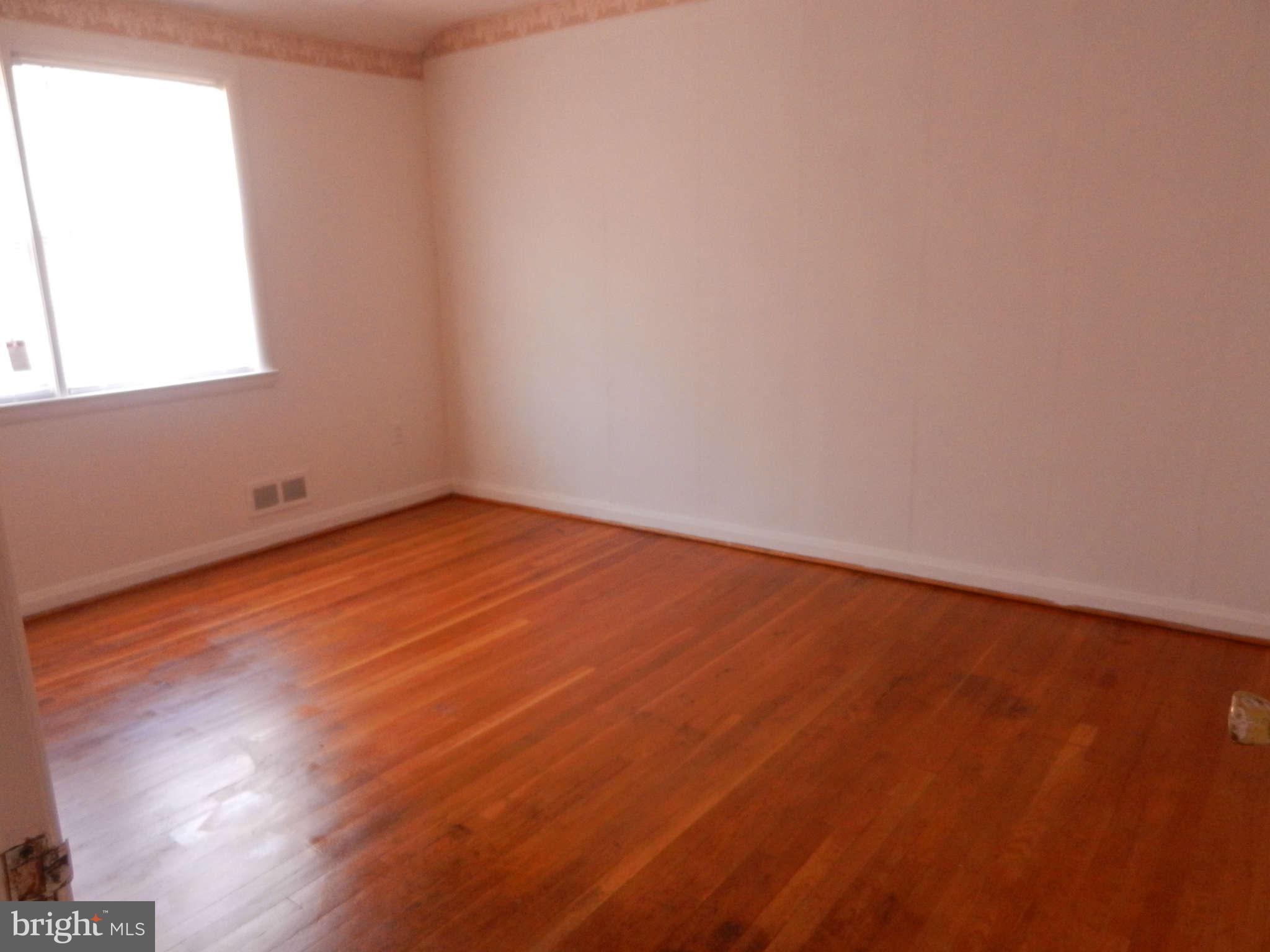 6124 Marlora Road Baltimore, MD 21239 - Photo 6 of 12 an empty room with wooden floor and windows