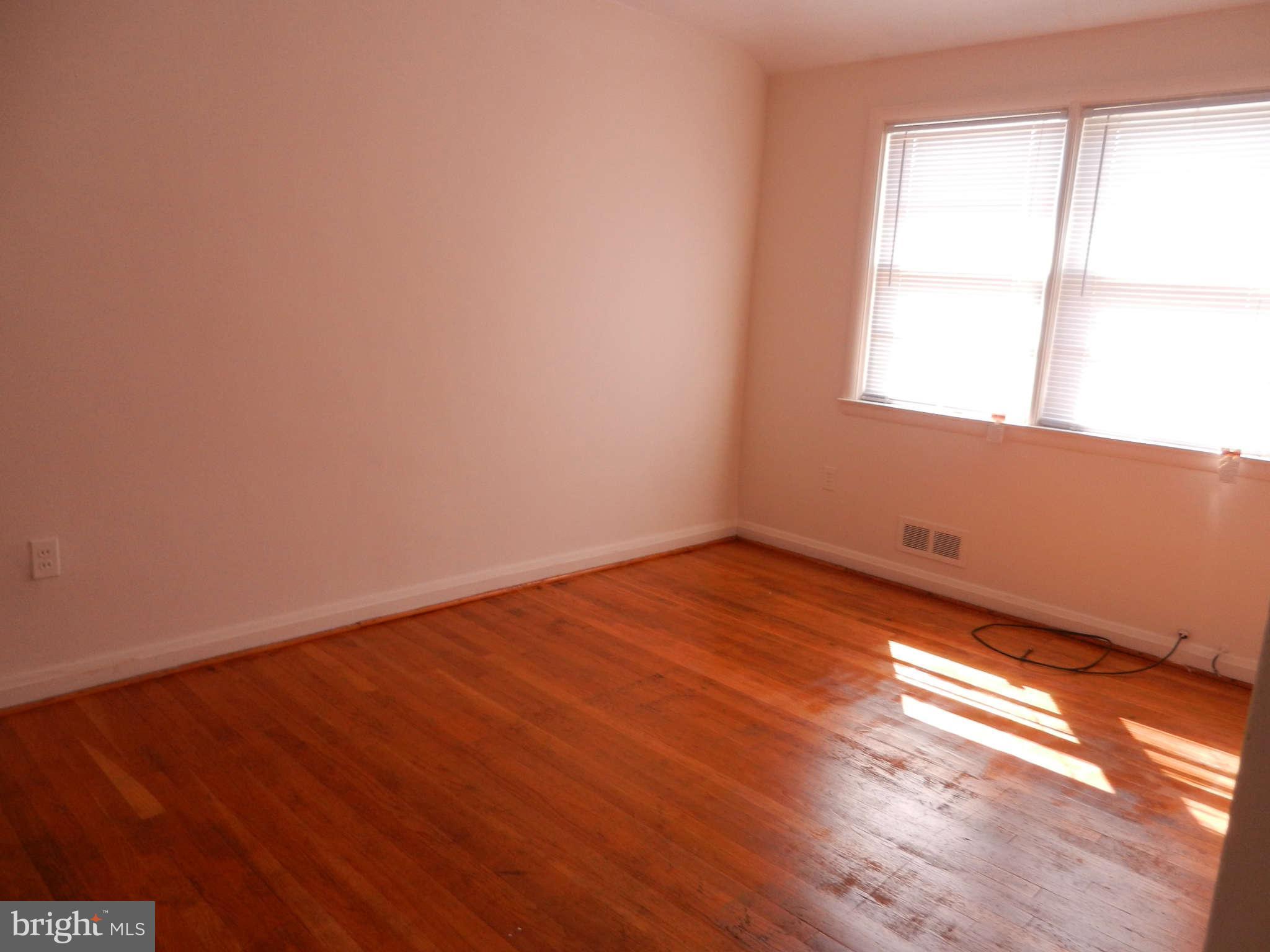 6124 Marlora Road Baltimore, MD 21239 - Photo 7 of 12 an empty room with wooden floor and windows