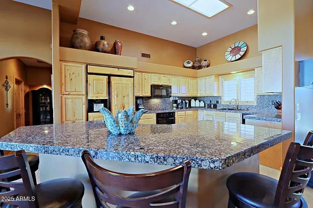 a kitchen with stainless steel appliances granite countertop a sink and a refrigerator