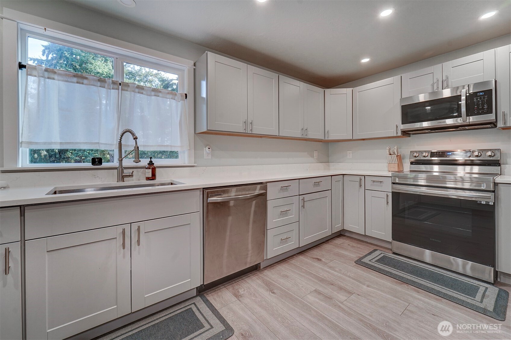4931 Knute Anderson Road Northwest Silverdale, WA 98383 - Photo 12 of 37 a kitchen with white cabinets stainless steel appliances and a sink