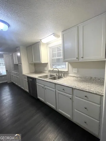 a kitchen with granite countertop white cabinets and sink