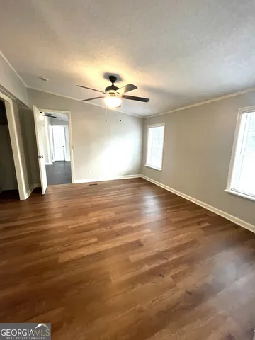 an empty room with wooden floor and windows
