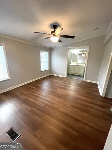 an empty room with wooden floor chandelier fan and windows