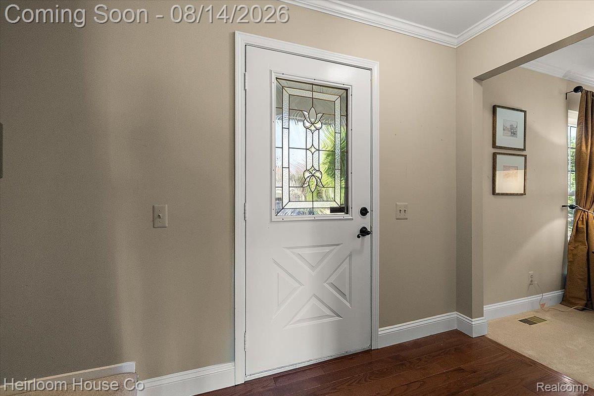 45697 Bryn Mawr Road Canton, MI 48187 - Photo 54 of 75 White entry door with decorative glass inlay, dark hardware, crown molding, and wood-finish flooring