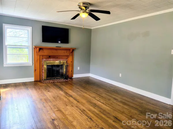 an empty room with windows fireplace and wooden floor