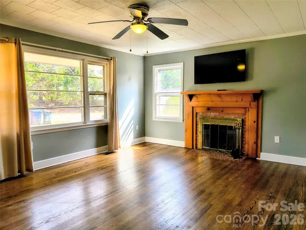an empty room with windows fireplace and a flat screen tv