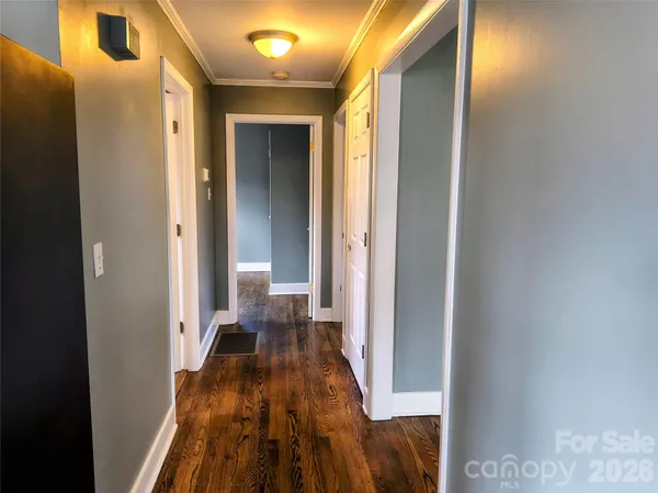 a view of a hallway with wooden floor and a bathroom