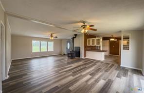 3627 North Katy Road Ross, TX 76640 - Photo 6 of 31 a view of an empty room and a kitchen with wooden floor and kitchen view