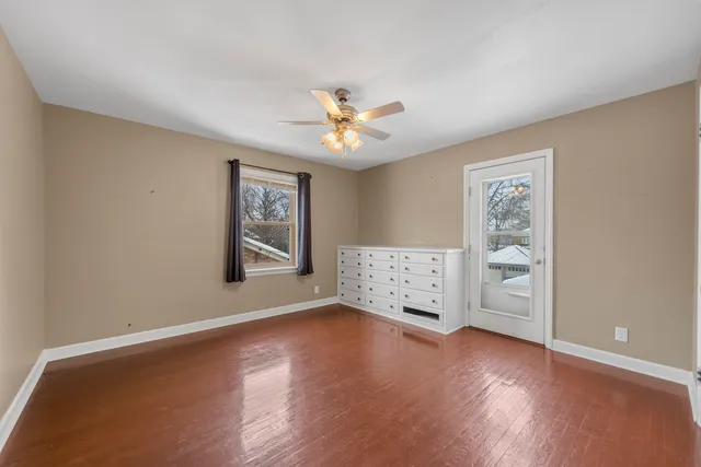 a view of an empty room with window and wooden floor