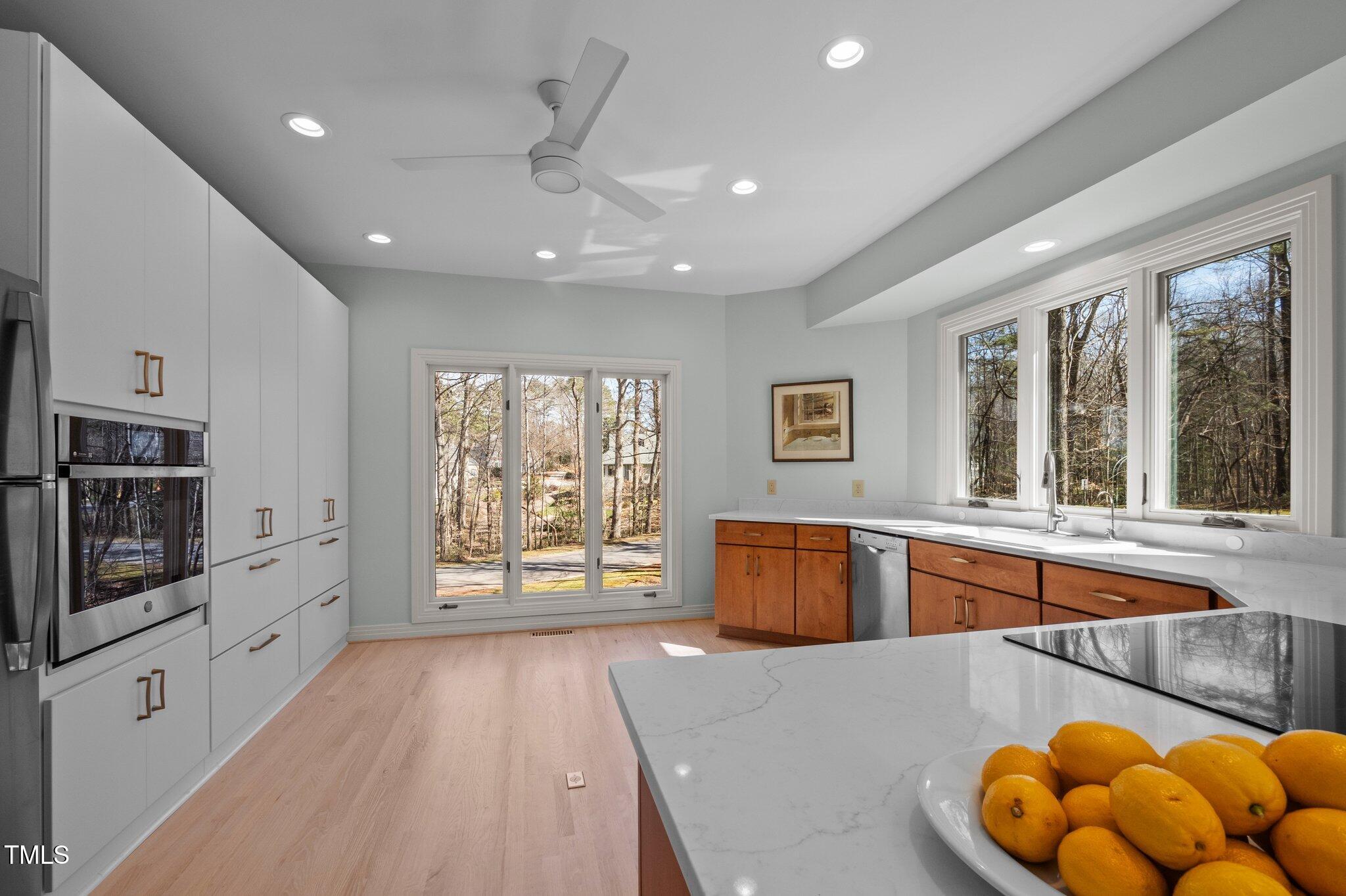 8804 Ross Court Raleigh, NC 27613 - Photo 12 of 38 a large white kitchen with wooden floors and stainless steel appliances