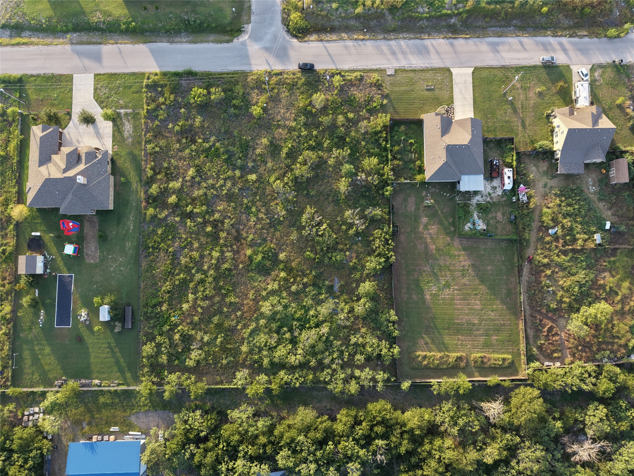 232 East Ridge Lane Kyle, TX 78640 - Photo 22 of 36 An aerial perspective reveals a vast, undeveloped lot nestled between residential properties, offering ample space for a custom build.