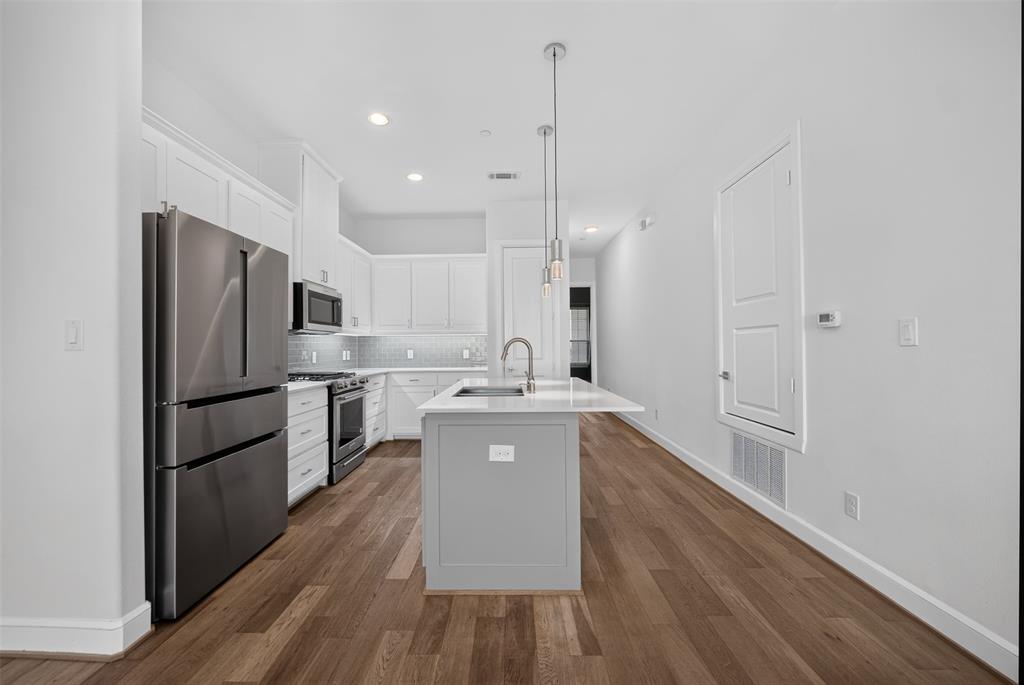 5015 Meridian Lane, Unit 2102 Addison, TX 75001 - Photo 8 of 36 Modern kitchen featuring wood-finish flooring, white cabinetry, and stainless steel appliances