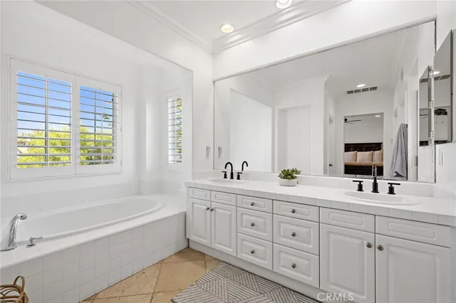 a bathroom with double vanity a windows a bathtub and a double vanity sink a mirror