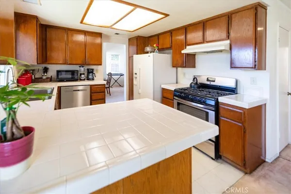a kitchen with stainless steel appliances kitchen island granite countertop a sink a stove and a refrigerator