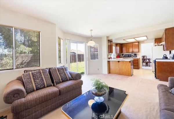 a living room with furniture kitchen view and a large window