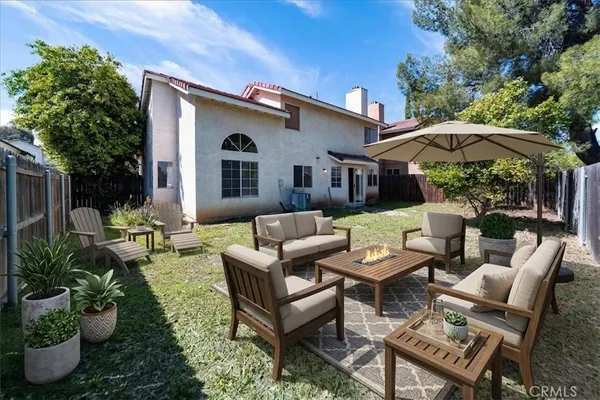 a view of a patio with couches table and chairs under an umbrella with a fire pit
