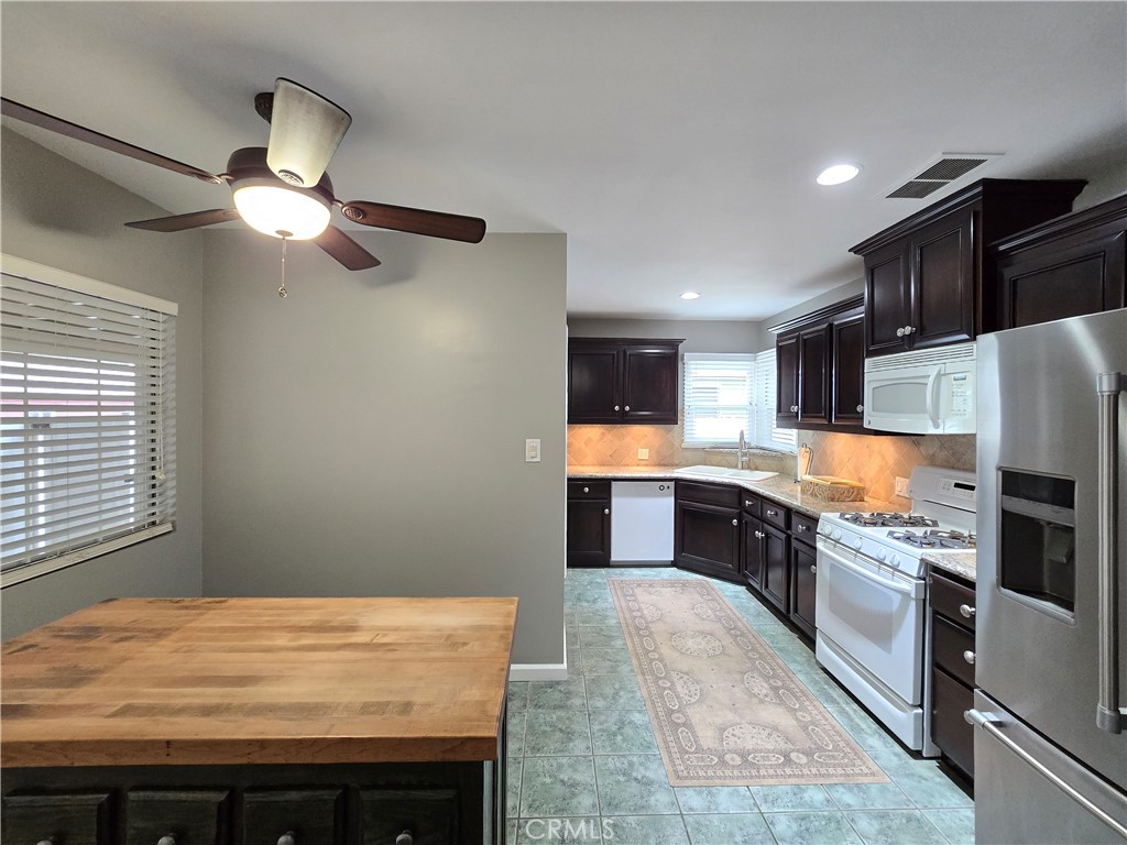 4651 Emerson Street Riverside, CA 92506 - Photo 9 of 32 a kitchen with stainless steel appliances granite countertop a refrigerator a sink dishwasher a stove and white cabinets with wooden floor