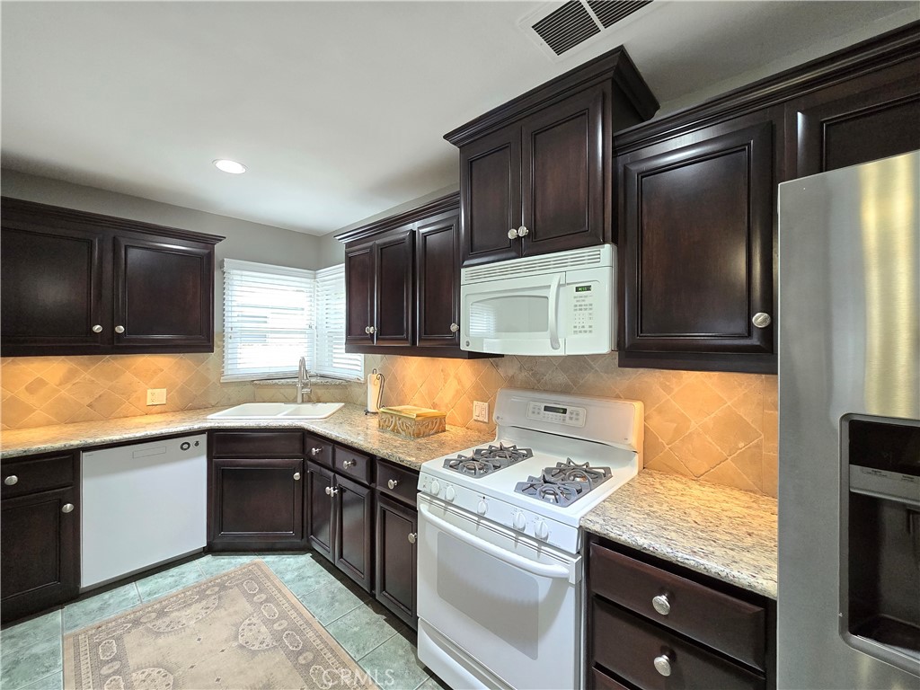 4651 Emerson Street Riverside, CA 92506 - Photo 10 of 32 a kitchen with stainless steel appliances granite countertop a sink stove refrigerator and cabinets