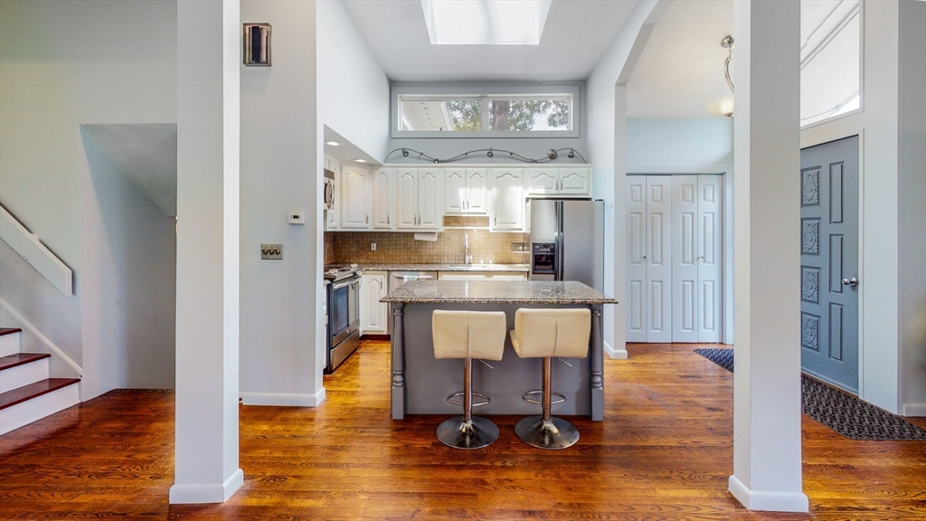 15 Carlin Road Waltham, MA 02451 - Photo 13 of 42 a kitchen with kitchen island a dining table chairs cabinets and wooden floor