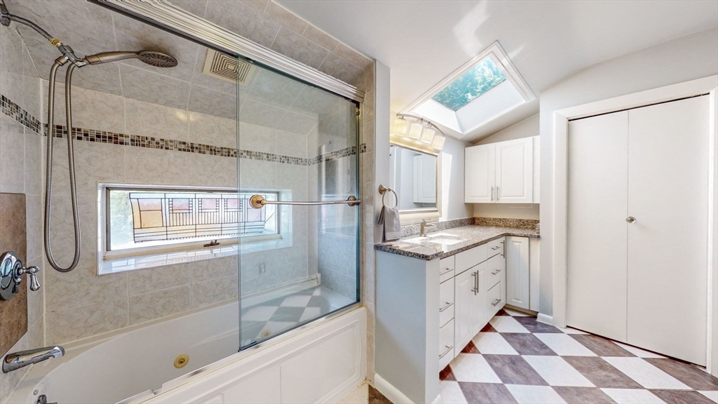 15 Carlin Road Waltham, MA 02451 - Photo 33 of 42 a bathroom with a granite countertop sink a mirror a bathtub and shower