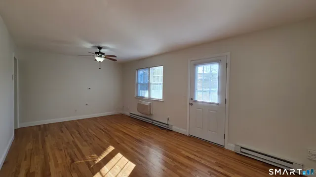 a view of an empty room with wooden floor and a window