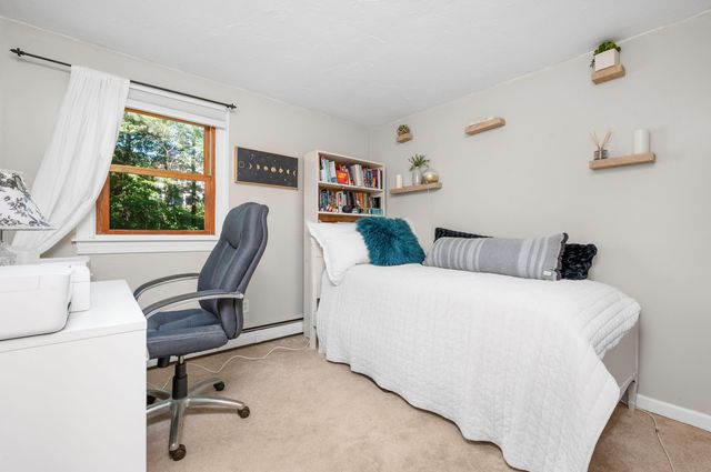 a bedroom with a bed a computer on desk and a dresser next to a window