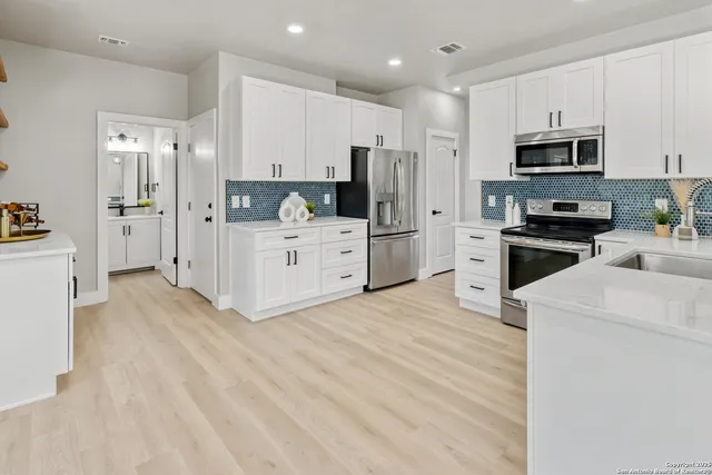 a kitchen with white cabinets and stainless steel appliances