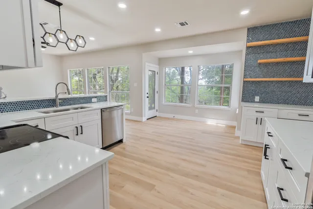 a kitchen with a sink a large window appliances and cabinets
