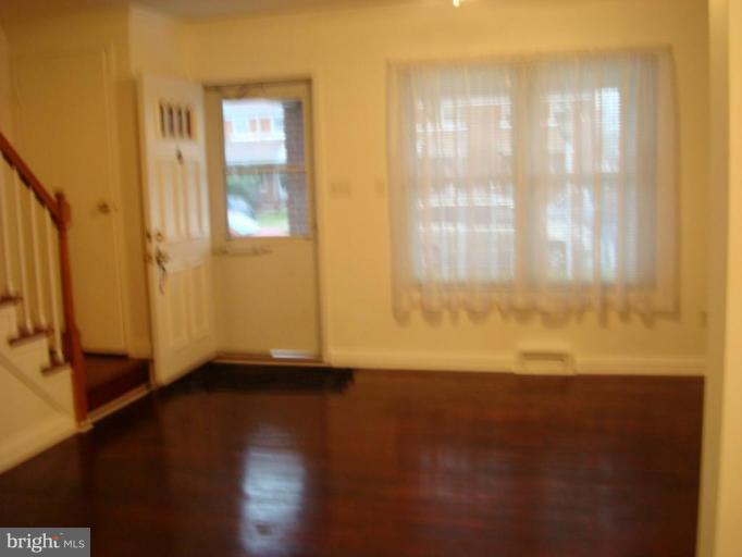 8013 Kimberly Road Dundalk, MD 21222 - Photo 2 of 12 a view of an empty room with wooden floor and a window
