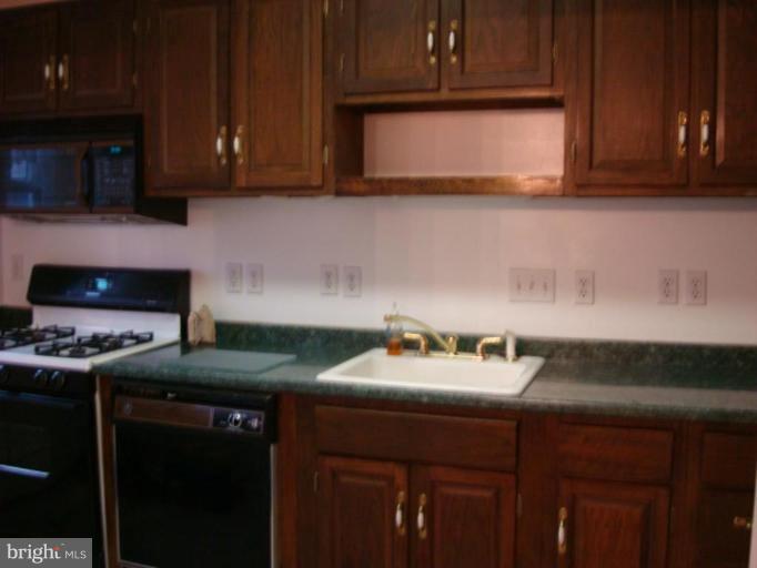 8013 Kimberly Road Dundalk, MD 21222 - Photo 4 of 12 a kitchen with stainless steel appliances granite countertop a stove a microwave oven and a sink with cabinets