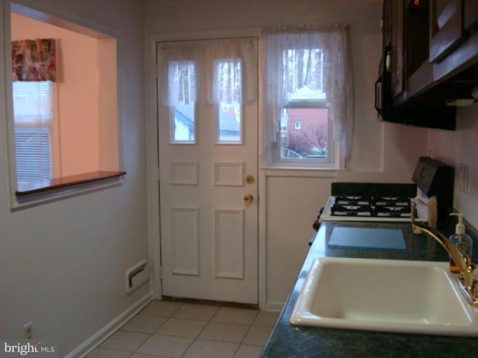 8013 Kimberly Road Dundalk, MD 21222 - Photo 5 of 12 a kitchen with white cabinets and black appliances