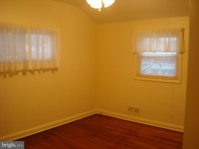 8013 Kimberly Road Dundalk, MD 21222 - Photo 6 of 12 an empty room with wooden floor and windows