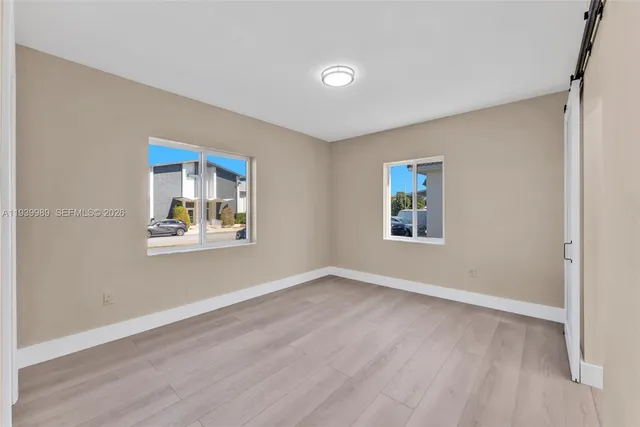 a view of an empty room with window and wooden floor