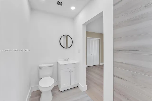 a bathroom with a toilet sink a mirror and vanity