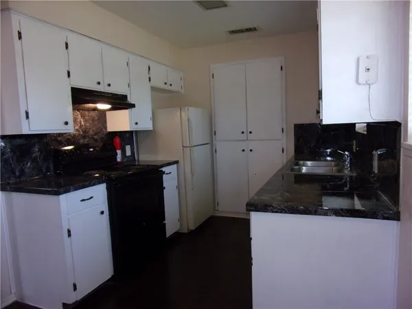 a kitchen with granite countertop white cabinets and black appliances