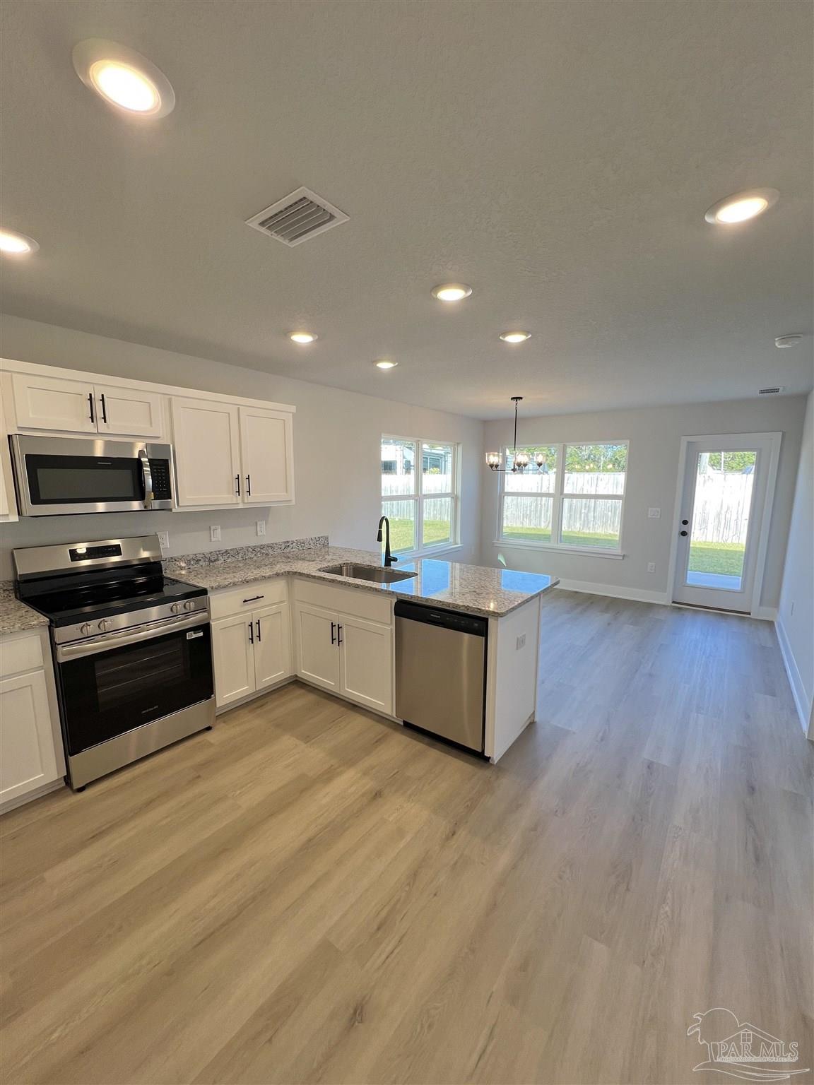 3327 Bliss Lane, Unit 12E Cantonment, FL 32533 - Photo 7 of 15 a large kitchen with stainless steel appliances granite countertop a stove a sink dishwasher and a oven with white cabinets