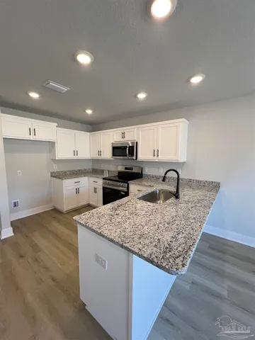 a kitchen with stainless steel appliances granite countertop a sink stove and cabinets