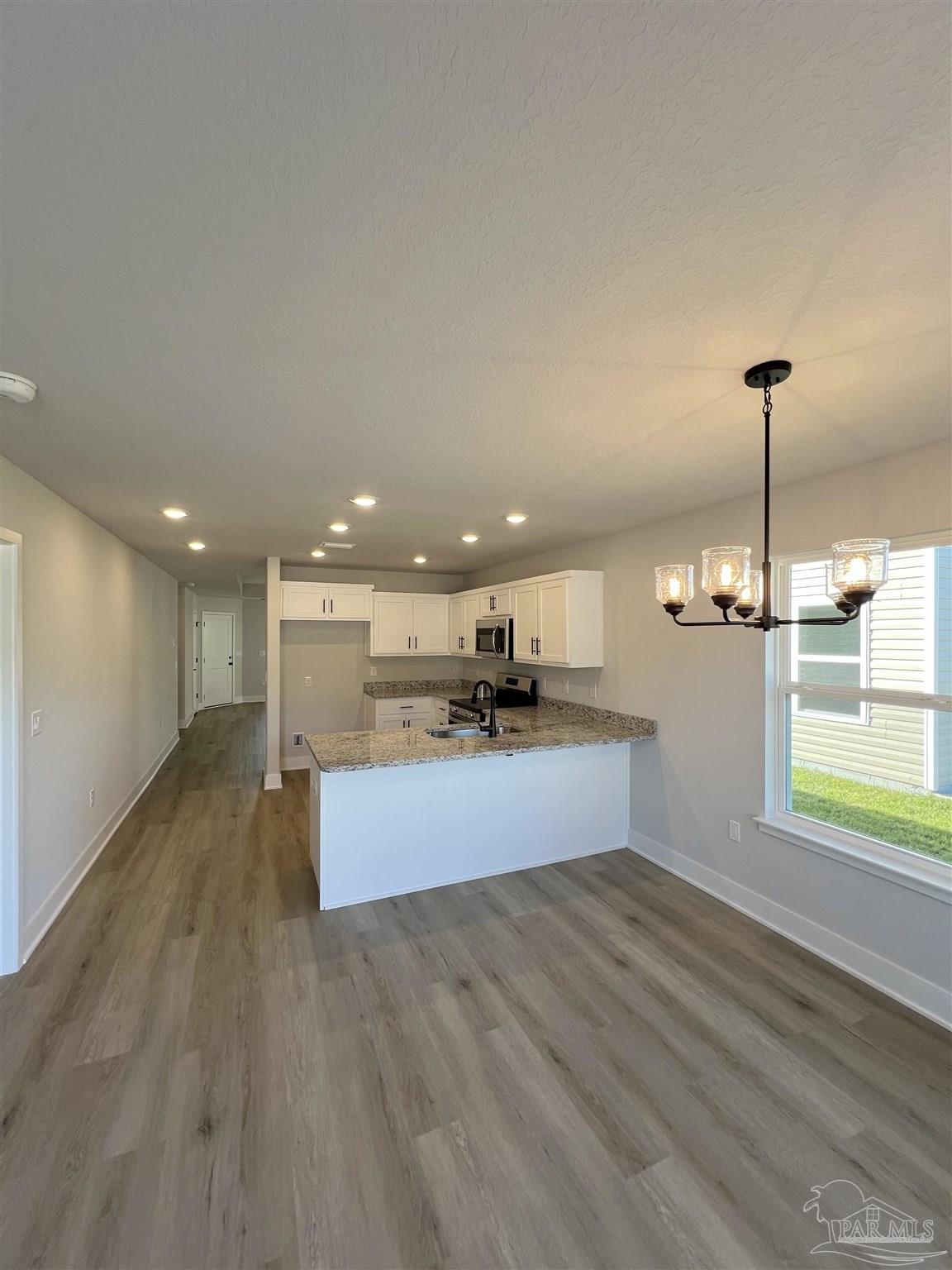 3327 Bliss Lane, Unit 12E Cantonment, FL 32533 - Photo 9 of 15 a large kitchen with stainless steel appliances kitchen island a large counter top and a wooden floors