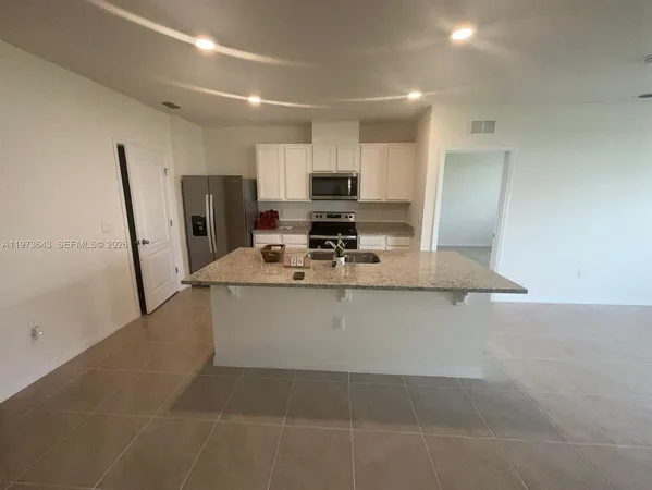 a view of kitchen with stainless steel appliances granite countertop a sink stove and refrigerator