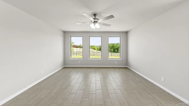 an empty room with windows and ceiling fan