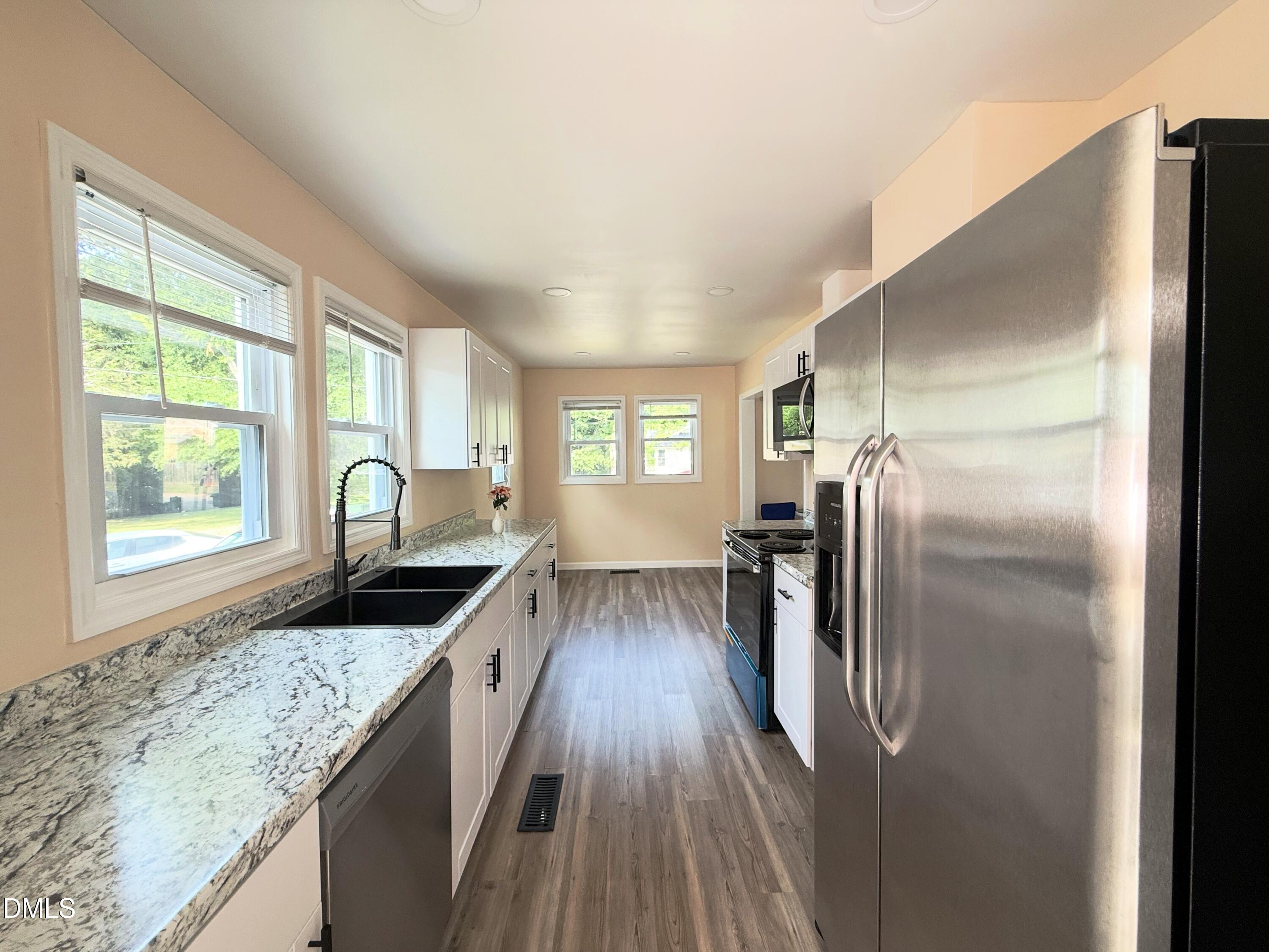 417 North Street Graham, NC 27253 - Photo 3 of 18 a kitchen with granite countertop a refrigerator a sink a stove and island with wooden floor