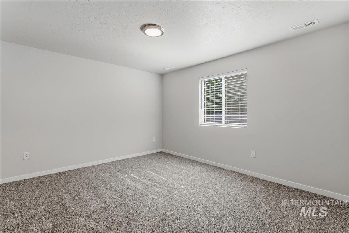 3091 S Green Boise, ID 83709 - Photo 12 of 27 Spacious room with light gray walls, new gray carpeting, and a white trim baseboard